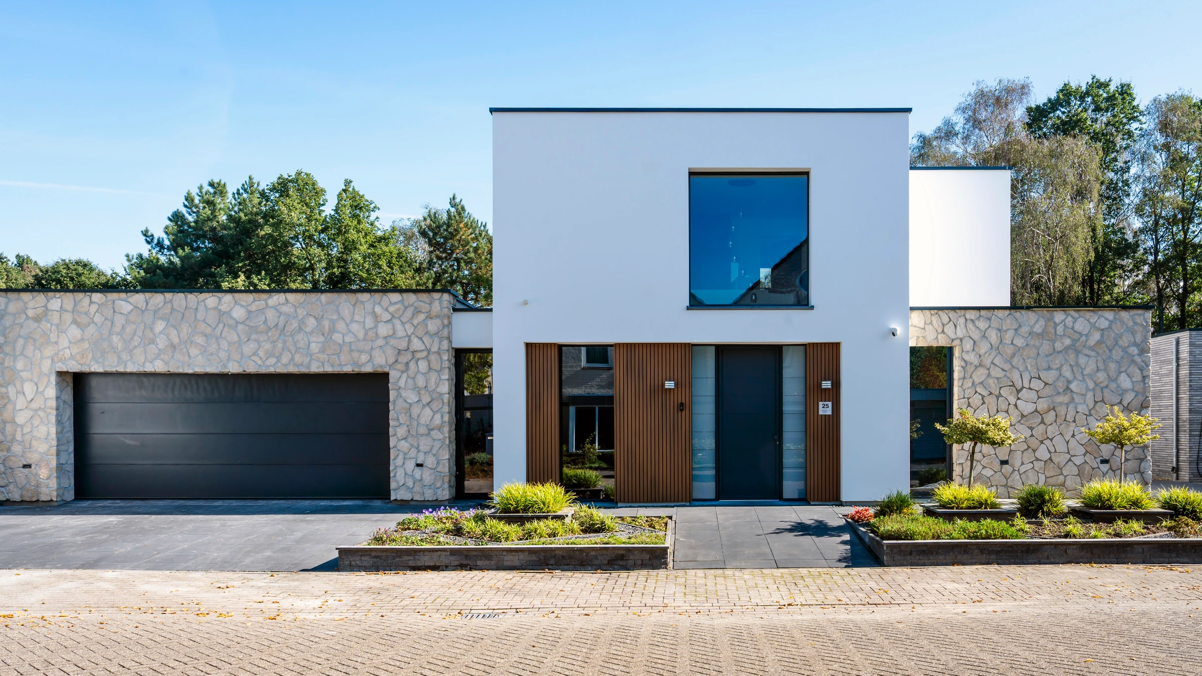 De vernieuwde voorgevel van de woning in Asten met witte afwerking en natuursteen